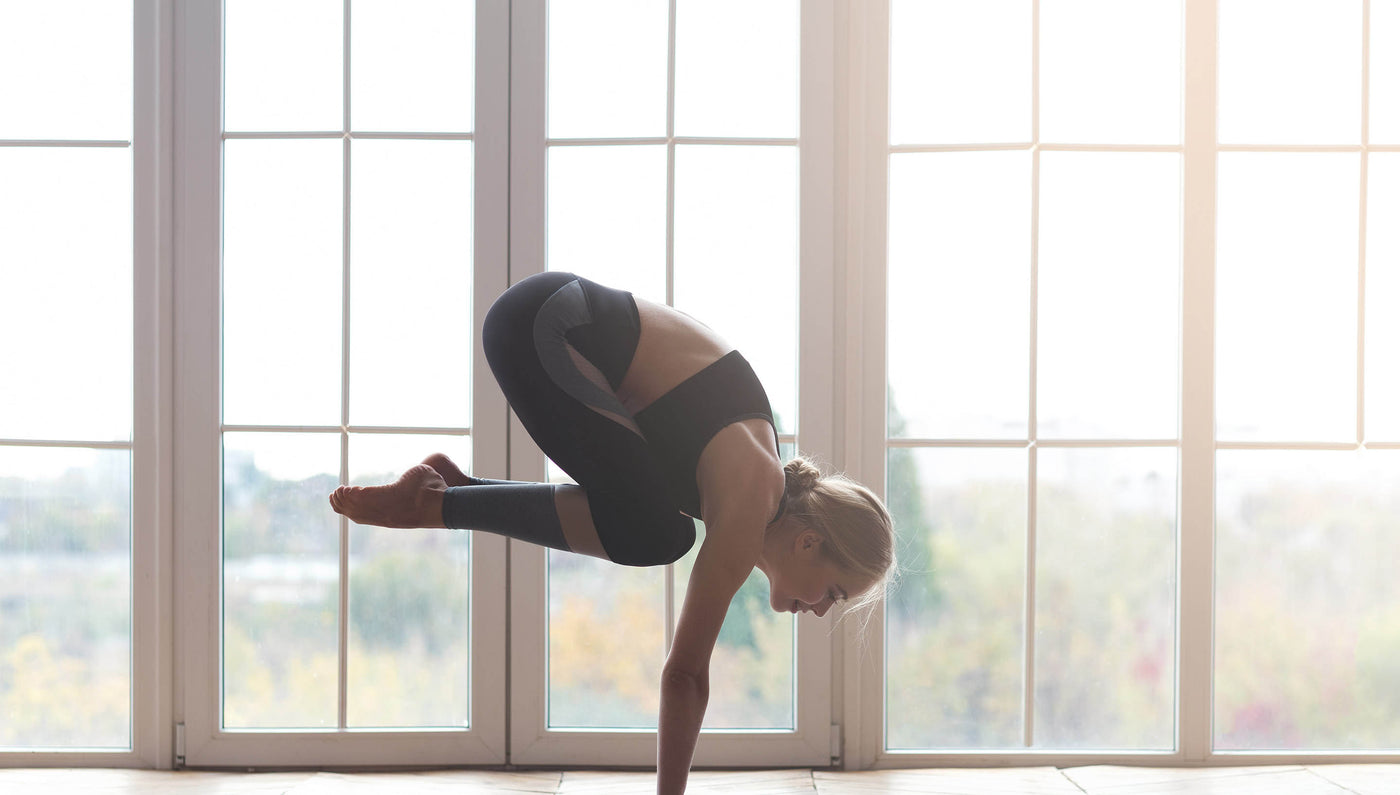 Blond woman doing difficult high crow yoga pose | Asana Singapore - The Ultimate Workout Mats