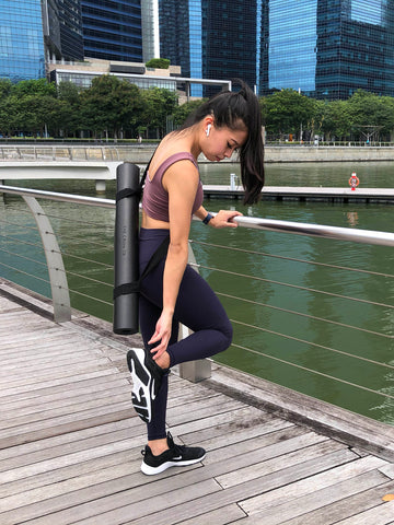 Fit Asian Woman Carrying The Crow TR Travel Ultimate Workout Mat With Strap by Asana Singapore