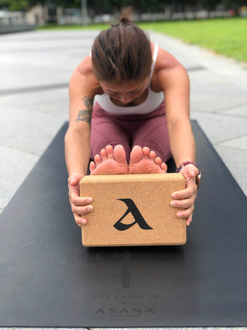 Woman in red athleisure stretching her legs propping thanks to The Cork Block Set by Asana Singapore