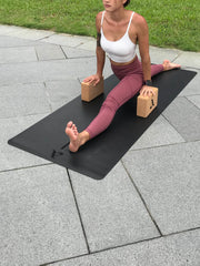 Woman in red athleisure wear stretching herself on a black yoga mat with The Cork Block Set by Asana Singapore